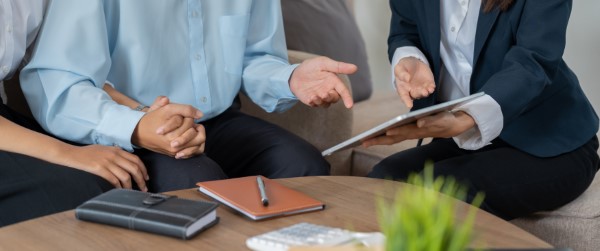 Cómo contratar un seguro; imagen de un asesor explicando a una pareja en qué consiste un seguro y sus beneficios.